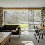 Living and dining area with wooden walls, sofa, table, and view of the garden.