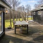 Deck with table and chairs, surrounded by forest and wooden walls.