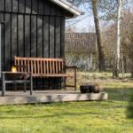 Wooden terrace with bench and fire pit in front of a dark wood house.