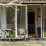 Terrace with table and two chairs in front of a glass door.