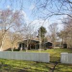 House with garden, white fence, and trees in the background.