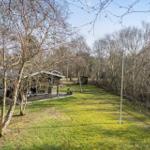 House with terrace, surrounded by grass and leafless trees.