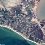 Aerial view of a coastal area with houses, beach, and water.