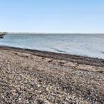 Rocky shore with calm water and clear sky view.