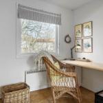 A workspace with desk, chair, and window. Four pictures hang on the wall.