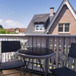 Terrasse mit Tisch und zwei Stühlen. Blick auf Haus mit Ziegelfassade.