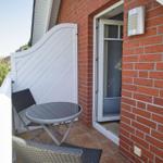 Terrasse mit Tisch und Stühlen neben rotem Backsteinhaus.