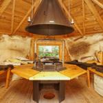 Holzvertäfelte Hütte mit Fellwand, zentraler Feuerkessel und Sitzbänken.