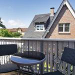 Terrasse mit Tisch und zwei Stühlen, Blick auf ein Haus mit Ziegelfassade und Dachgauben.