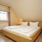 Schlafzimmer mit Doppelbett, Fenster und Nachttischen.