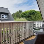 Terrasse mit Tisch und Stühlen, Blick auf Grün und Nachbarhaus.
