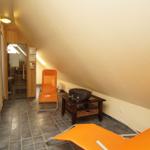 Dachgeschosszimmer mit zwei orangefarbenen Liegestühlen und einem Holztisch.