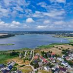 Aerial view of a lake with surrounding residential areas and green fields under a partly cloudy sky.