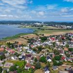 Aerial view of a coastal town with houses, fields, and a large water body.