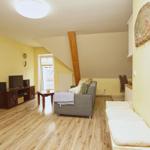 Wohnzimmer mit Sofa, Fernseher und Holzboden. Anbau mit Küchenbereich.