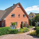 Rotes Backsteingebäude mit Gartenterrasse und gepflegtem Garten.
