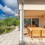 Terrasse mit Holztisch und Stühlen, Blick auf einen Teich und Garten.