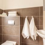 Badezimmer mit Toilette, Waschbecken und Handtüchern.