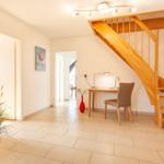 Eingangsbereich mit Holztreppe, Schreibtisch und Pflanzen.
