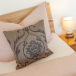 Bettkopfteil aus Holz, Kissen und Nachttisch mit Lampe.