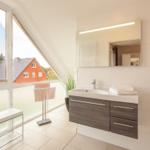 Badezimmer mit Dachschrägenfenster, Waschbecken und Spiegel