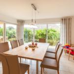 Esszimmer mit Holztisch, Stühlen und Blick auf Garten. Kindertisch und -stühle sind vorhanden.