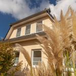 Ein zweistöckiges Haus mit Fenstern und Pflanzen im Vordergrund.