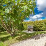 Garten mit Feigenbaum und Steinofen. Grasfläche und Kiesweg.