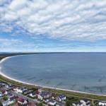 Aerielansicht eines Strandes mit Häusern und Meer unter bewölktem Himmel