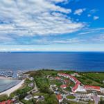 Hafen mit Booten, Strand und roten Dächern an der Küste.