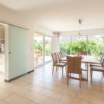 Essbereich mit Tisch und Stühlen, Küchenbereich und Terrasse mit Blick auf Garten.