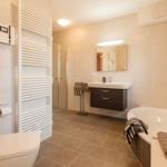 Badezimmer mit Badewanne, Dusche, Waschbecken und Heizkörper.