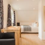 Schlafzimmer mit Bett, Schreibtisch und Spiegel.