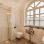 Badezimmer mit Dusche, Toilette und Fenster.