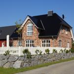 Ein rotes Backsteingebäude mit weißem Zaun und Steinmauer.