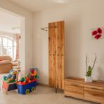 Zimmer mit Kleinkindmöbeln, Holzschrank und Blumendekoration.