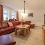 Ein Wohnzimmer mit rotem Ledersofa, Holztisch und Fernseher.