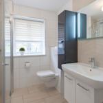 Badezimmer mit Dusche, WC und Waschbecken.