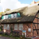 Traditionelles Haus mit Strohdach und Backsteinfassade im Herbst.