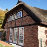 Rotes Backsteingebäude mit Strohdach und weißen Fenstern.