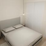Schlafzimmer mit Bett, Kleiderschrank und zwei Hängelampen.