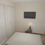 Schlafzimmer mit Bett, TV, Kleiderschrank und Fenster mit Jalousie.
