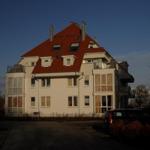 Wohnhaus mit rotem Dach und mehreren Fenstern im Abendlicht.
