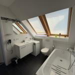 Badezimmer mit Dusche, Badewanne und Dachfenstern.