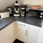 Küchenzeile mit Toaster, Kaffeemaschine, Mikrowelle und Korb.