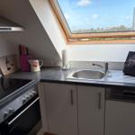 Küche mit Dunstabzugshaube, Spüle und Fenster. Geräte sind vorhanden.