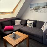 Ein Wohnbereich mit dunkelgrauem Sofa, Holztisch und Dachfenster.