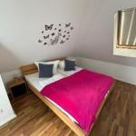 Schlafzimmer mit Holzboden, Bett und Wanddekoration.