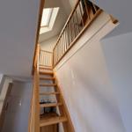 Holztreppe führt zur oberen Etage mit Dachfenster.