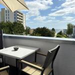 Terrasse mit Tisch und Stühlen, Blick auf Meer und Gebäude.